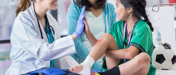 a little girl getting her shin wrapped by a doctor